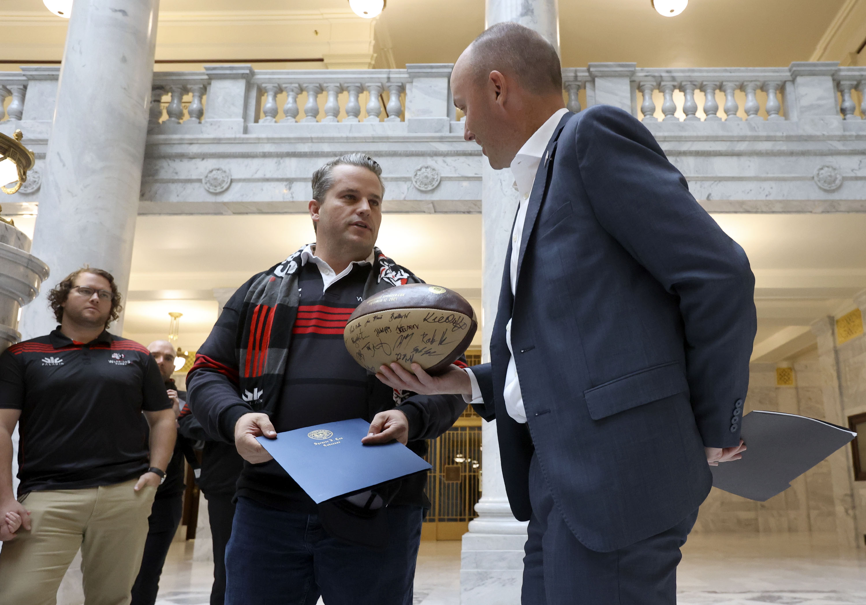 Kimball Kjar, Utah Warriors CEO, gives Gov. Spencer Cox a rugby ball signed by the Utah Warriors as Cox meets with the professional rugby team at the Capitol in Salt Lake City on Tuesday, Oct. 12, 2021.