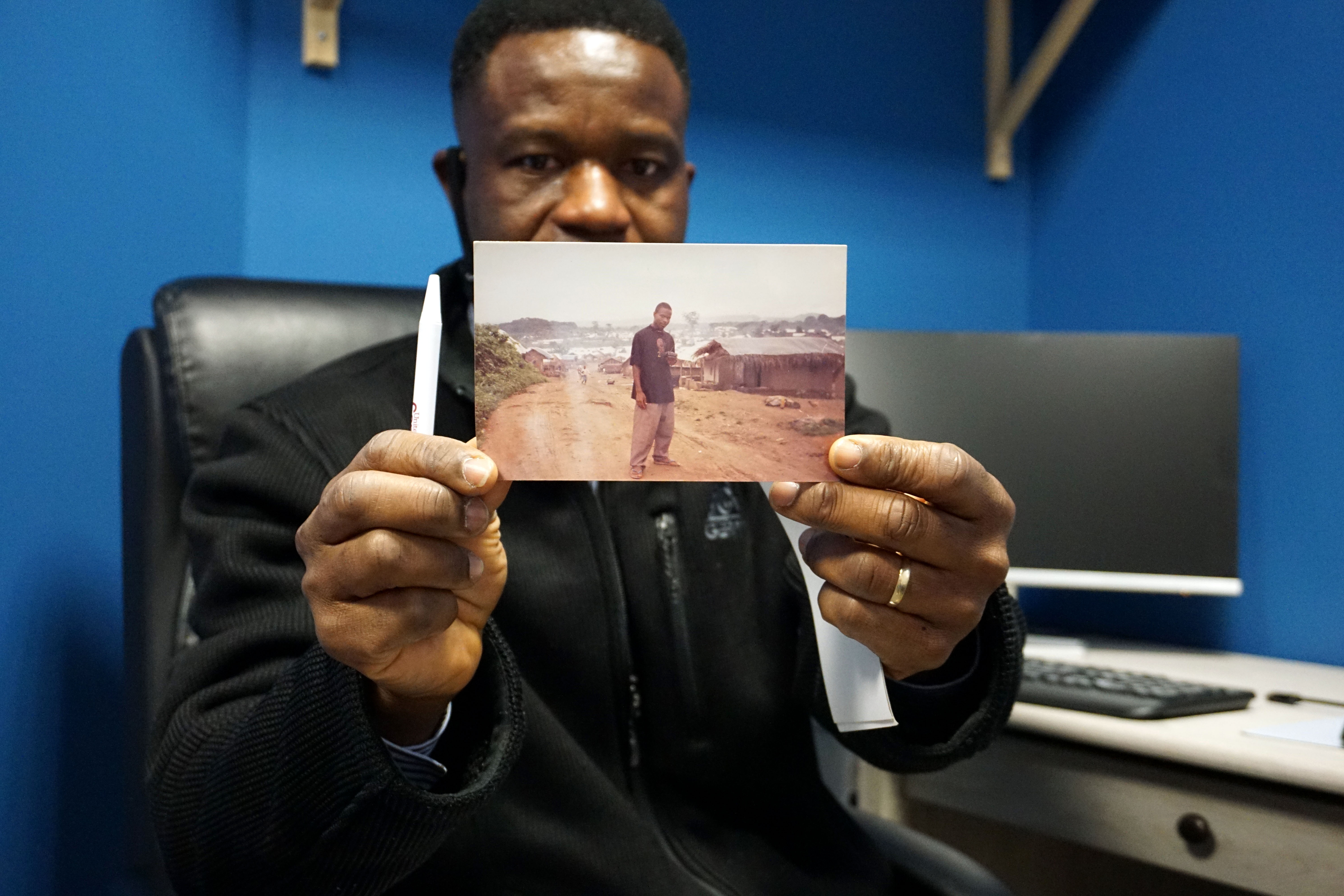 Salt Lake County’s New American and Refugee Liaison Joseph Genda shows a picture of himself at a refugee camp in Guinea.