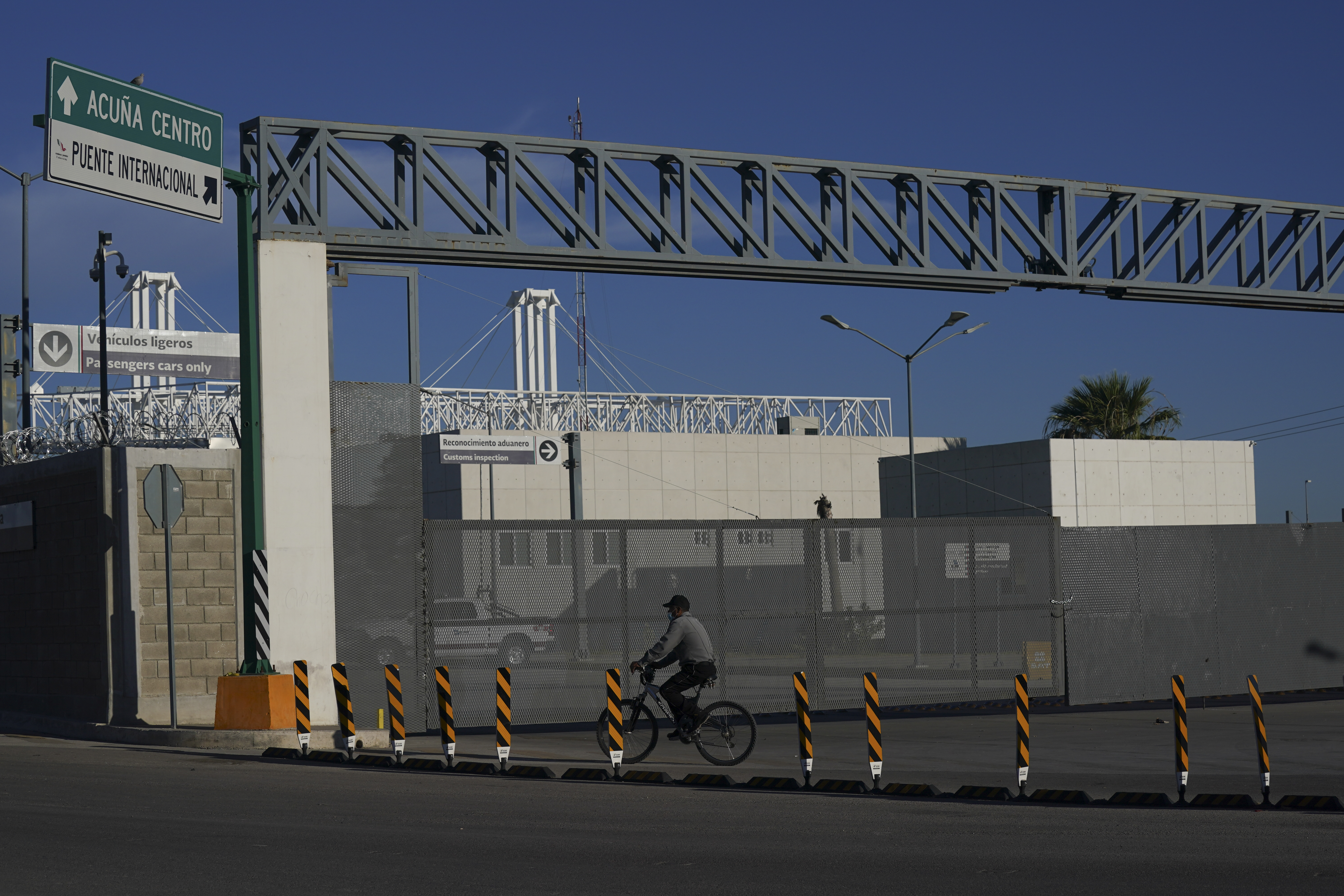 A man rides his bike past the closed main entrance of the international border bridge that connects the cities of Del Rio, Texas and Ciudad Acuna, Mexico, on Friday, on Sept. 24, 2021.