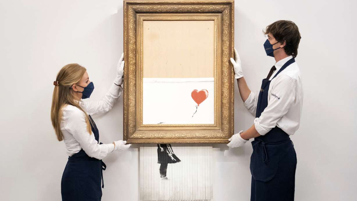 Art handlers at Sotheby's auction house hold Banksy's 'Love is in the Bin', before it returns to auction at Sotheby's, London, on Sept. 3. The work by British street artist Banksy that sensationally self-shredded just after it sold for $1.4 million made several times that price, $25.4 million, at an auction on Thursday.