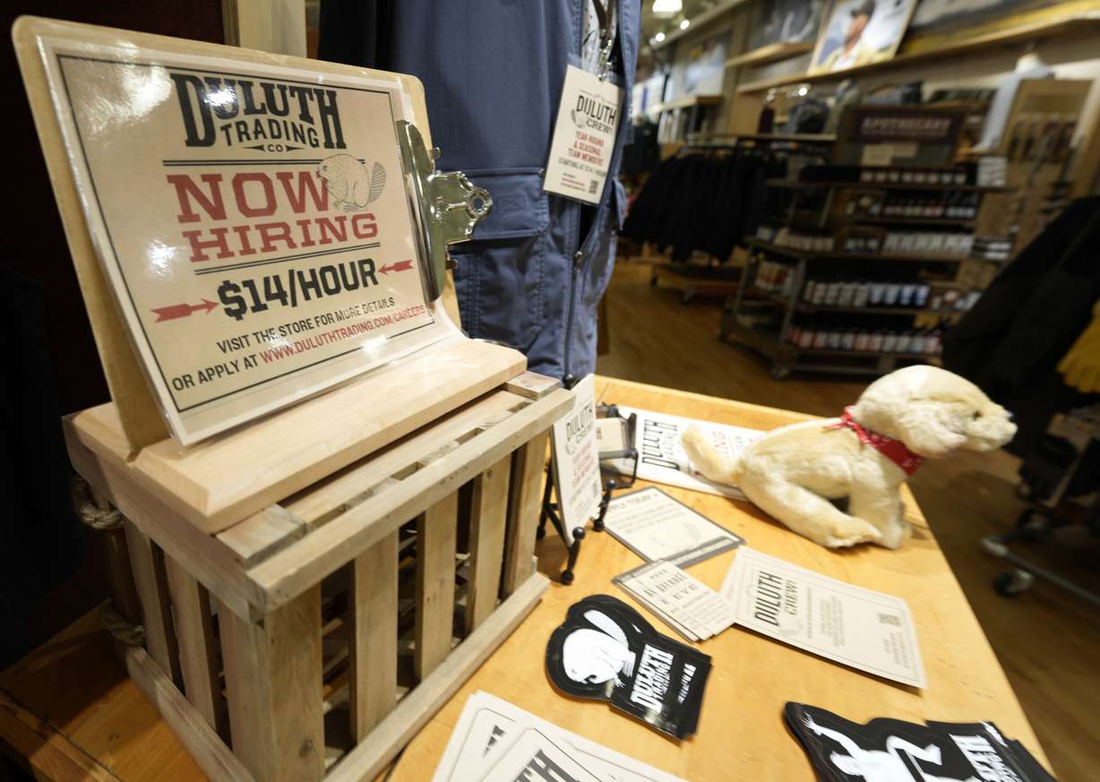 A now hiring sign sits on a display in a clothing store Saturday, in Sioux Falls, S.D. The number of Americans applying for unemployment benefits fell to its lowest level since the pandemic began, a sign the job market is still improving even as hiring has slowed in the past two months.