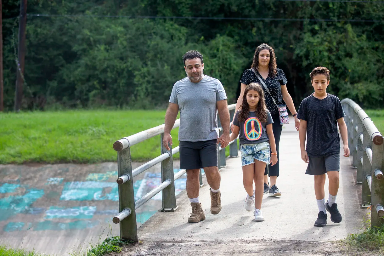 Mohammed Ghanayem walks with daughter Zayna Ghanayem, 9, wife Layla Kaiksow and son Nishan Ghanayem, 12, along a path in Kingwood, Texas, on Oct. 3. Mohammed and Layla take their kids to school using the same path and have found, on several occasions, racist graffiti. The green paint shows areas that have been painted over.