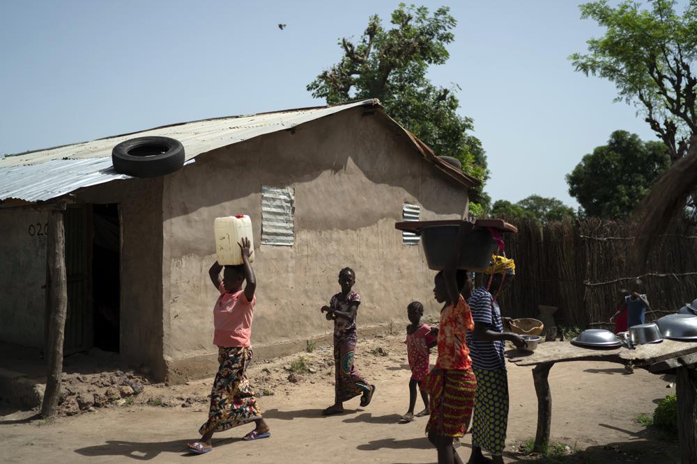 Lama Mballow carries a gallon of water collected from a local well at the Sare Gibel village in Bansang, Gambia, Wednesday, Sept. 29, 2021. Mballow, who has a 4-year-old son and another child on the way, has no plans to get vaccinated after giving birth. The persistent rumor that COVID-19 vaccines affect fertility has been especially troublesome in predominantly Muslim countries like Gambia and Somalia were polygamy is common. 
