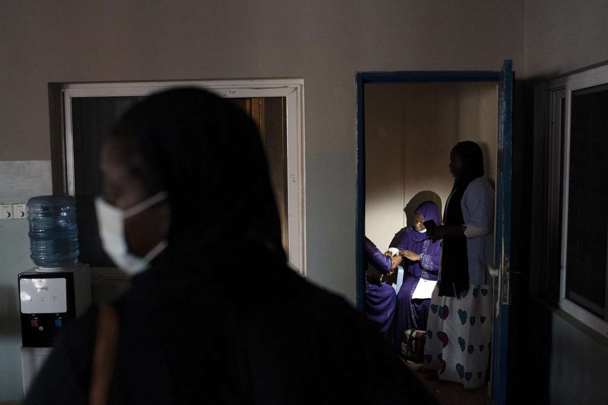 Lit by a mobile phone, a pregnant woman is assisted at the Bundung Maternal and Child Health Hospital in Serrekunda, outskirts of Banjul, Gambia, Friday, Sept. 24, 2021.