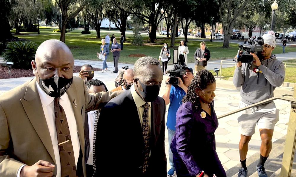 Ahmaud Arbery's father Marcus Arbery, center, heads into the Glynn County Courthouse in Brunswick, Georgia, with his attorney Benjamin Crump on Monday. Jury selection got underway with hundreds of people ordered to report for what could be a long, laborious effort to find jurors to hear the trial of three white men charged with fatally shooting Ahmaud Arbery as he was running in their neighborhood.