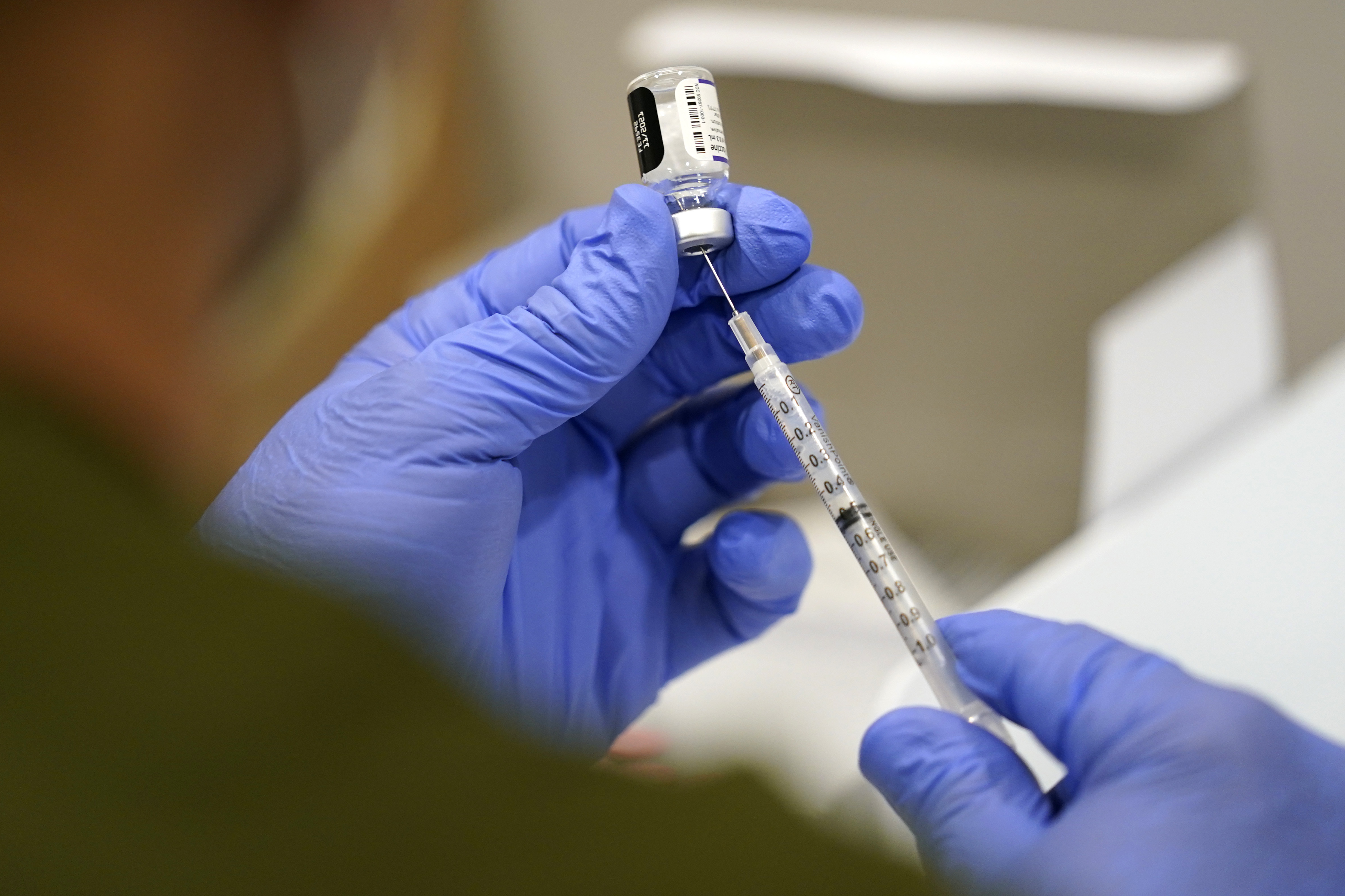 A health care worker fills a syringe with the Pfizer COVID-19 vaccine at Jackson Memorial Hospital in Miami on Oct. 5. The government is close to publishing the details of a new vaccination-or-testing rule covering more than 80 million Americans at companies with 100 or more workers. 
