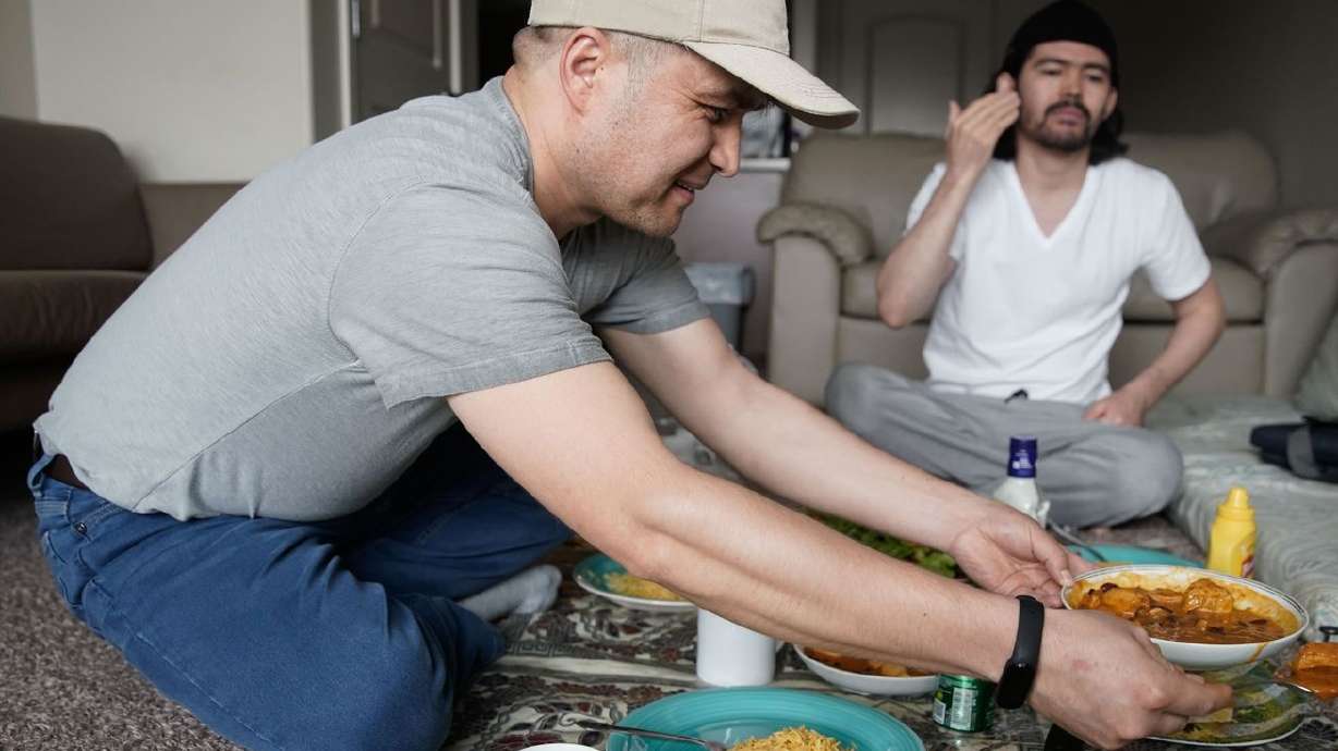 Azim Kakaie, front, serves lunch to his flatmate, Hussain Yaqobi, in the living room of their home in Salt Lake City
on Wednesday, Oct. 13, 2021. Kakaie, who worked as an air traffic controller at the Hamid Karzai International Airport in Kabul, fled Afghanistan following the Taliban takeover and arrived in Utah on Sept. 1.
