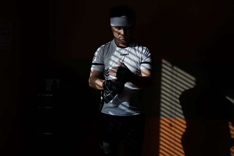 Azim Kakaie puts on his workout gloves before his
weekly workout session at his home’s gym in Salt Lake City on Oct. 13.