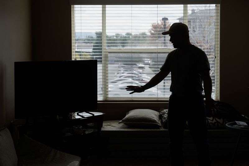 Azim Kakaie, who is waiting to be reunited with family,
is silhouetted against the window of the living room where he
currently resides in Salt Lake City on Oct. 13.