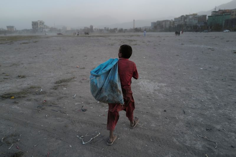 Eftekhar, 14, carries a bag filled with plastic bottles he collected, to be sold, as he walks in a playground in Kabul, Afghanistan, Oct. 22.