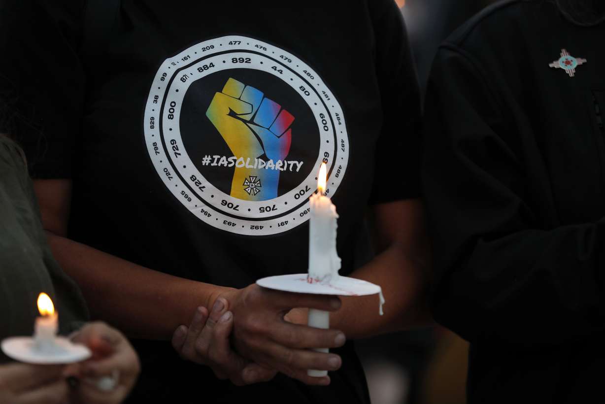 Movie industry worker Hailey Josselyn, wearing a T-shirt of the International Alliance of Theatrical Stage Employees (IATSA), holds a candle during a vigil to honor cinematographer Halyna Hutchins in Albuquerque, N.M., on Oct. 23.