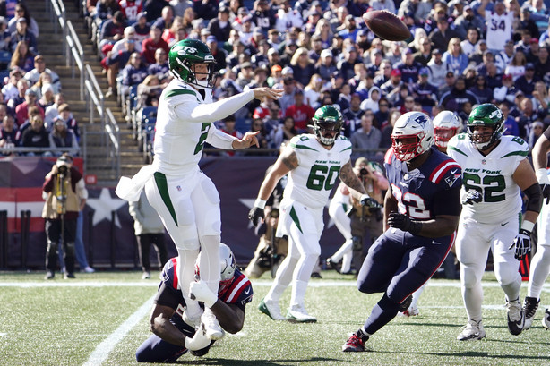 New York Jets quarterback Zach Wilson (2) passes the ball as New England Patriots defensive tackle Christian Barmore (90) grabs his ankles during the first half of an NFL football game, Sunday, Oct. 24, 2021, in Foxborough, Mass. At right is New England Patriots free safety Devin McCourty.