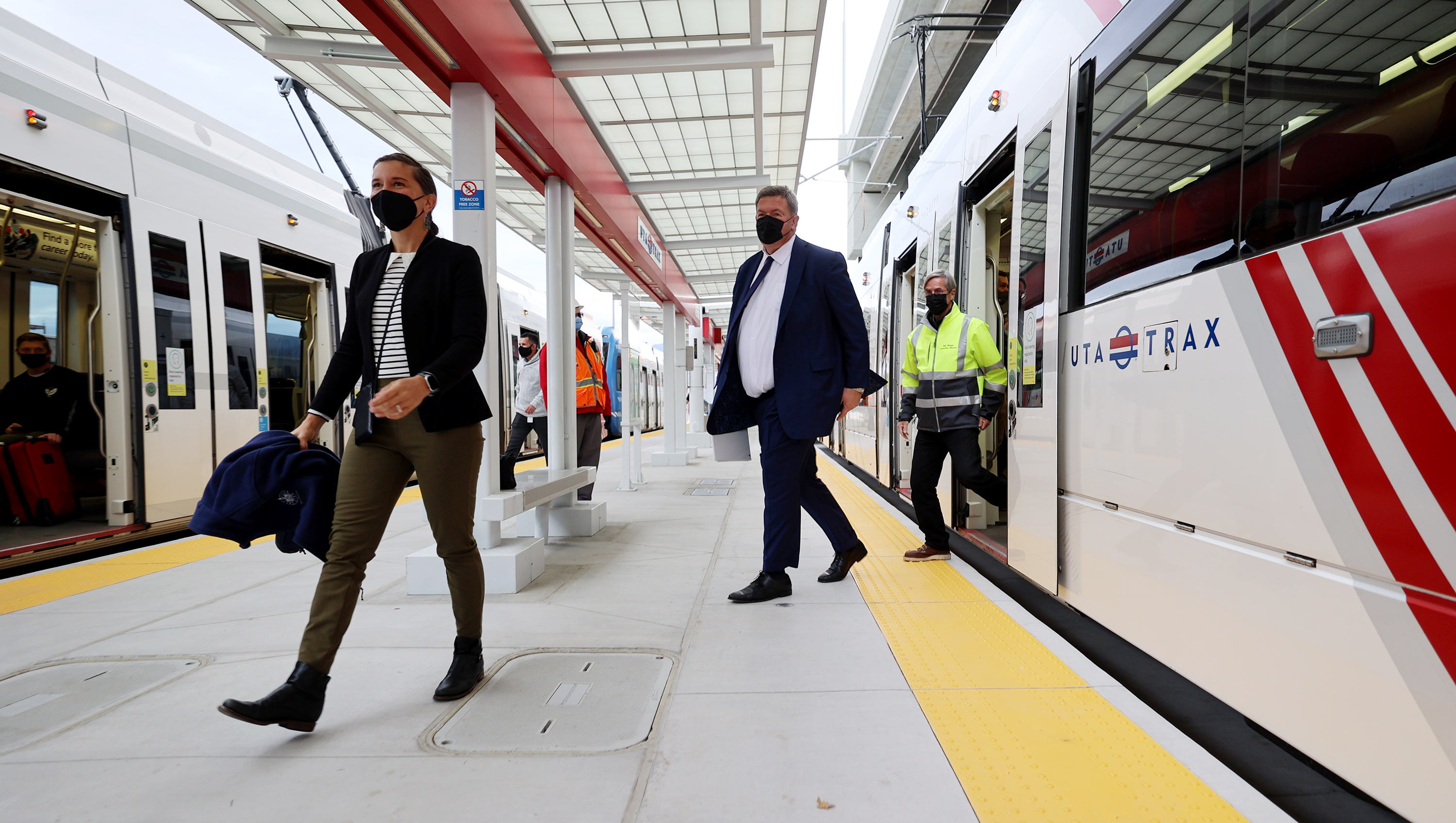 Salt Lake City Mayor Erin Mendenhall, Carlton Christensen, chairman of the board of trustees at Utah Transit Authority, and Bill Wyatt, executive director of the Salt Lake City International Airport, and other officials walk off a train as they gather to celebrate the new UTA TRAX airport station, marking the culmination of 20 months of construction extending TRAX to the new airport terminal, in Salt Lake City on Monday, Oct. 25, 2021.