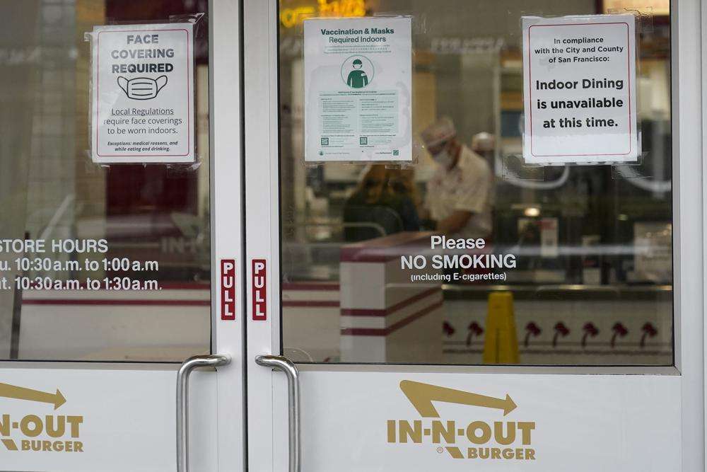 In this Oct. 20, 2021 photo, signs advising vaccination and face mask requirements and no indoor dining are displayed on the door of an In-N-Out restaurant in San Francisco's Fisherman's Wharf. The restaurant's indoor dining was shut down this month by health authorities for not demanding proof of vaccination.