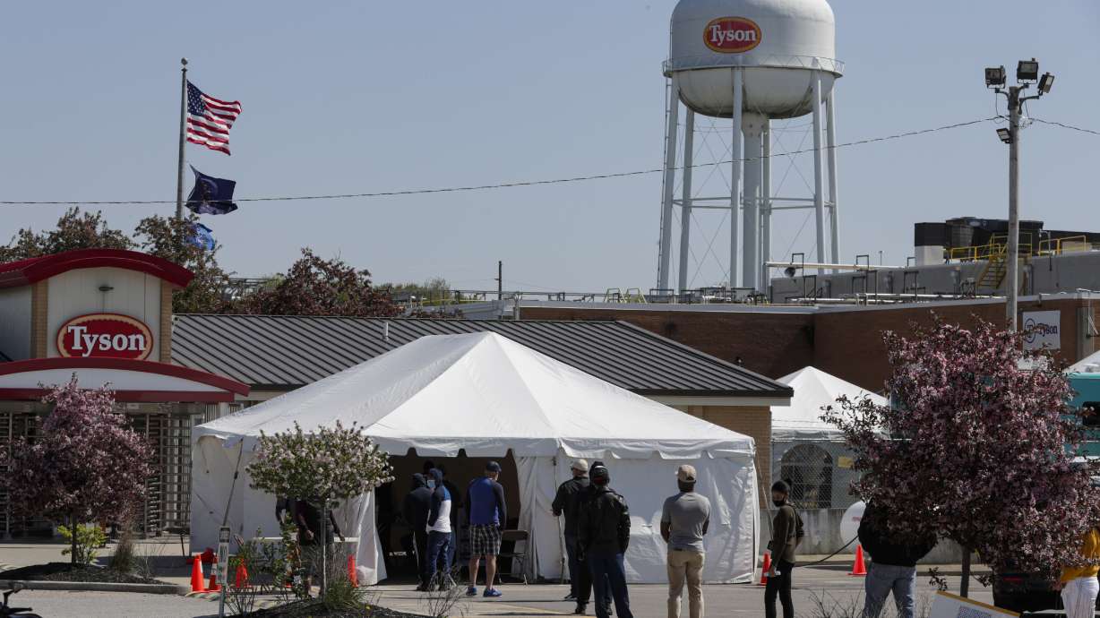 Workers wait in line to enter the Tyson Foods pork processing plant in Logansport, Ind., May 7, 2020. At least 59,000 meatpacking workers became ill with COVID-19 and 269 workers died when the virus tore through the industry last year, which is significantly more than previously thought, according to a new U.S. House report released Wednesday.