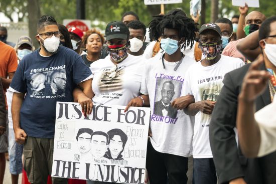 In this May 16, 2020 photo, Ahmaud Arbery's aunt Theawanza Brooks, center left, joins other family members and supporters in a march from the Glynn County Courthouse to a police station after a rally to protest the shooting of Arbery, in Brunswick, Ga. A pivotal defense argument of the three white men on trial for killing Ahmaud Arbery, a Black jogger, is that they were trying to make a citizen's arrest under a Civil War-era law.