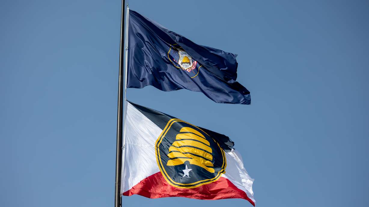 The Utah state flag, top, and the new commemorative state flag, below, fly atop the Capitol in Salt Lake City on July 13. The effort to rebrand Utah's flag is gaining traction months after state leaders launched a task force to come up with a new flag design.