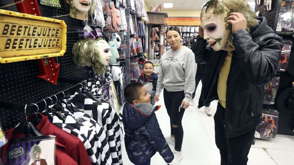 Gustavo Guarneros, left, Dominic Guarneros and Martha
Guarneros watch as Alex Aguiniga tries on a Beetlejuice mask while
shopping for Halloween costumes at Spirit Halloween in Millcreek on
Tuesday, Oct. 12.