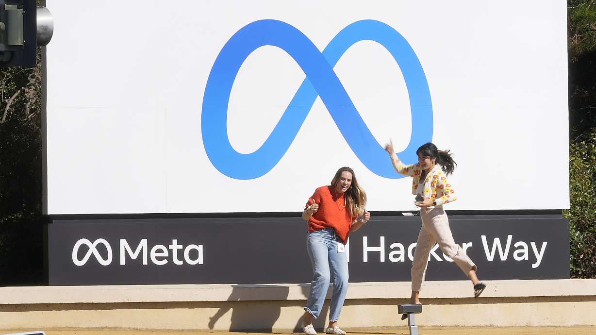 Facebook employees take a photo with the company's new name and logo outside its headquarters in Menlo Park, Calif., Thursday, after the company announced that it is changing its name to Meta Platforms Inc.