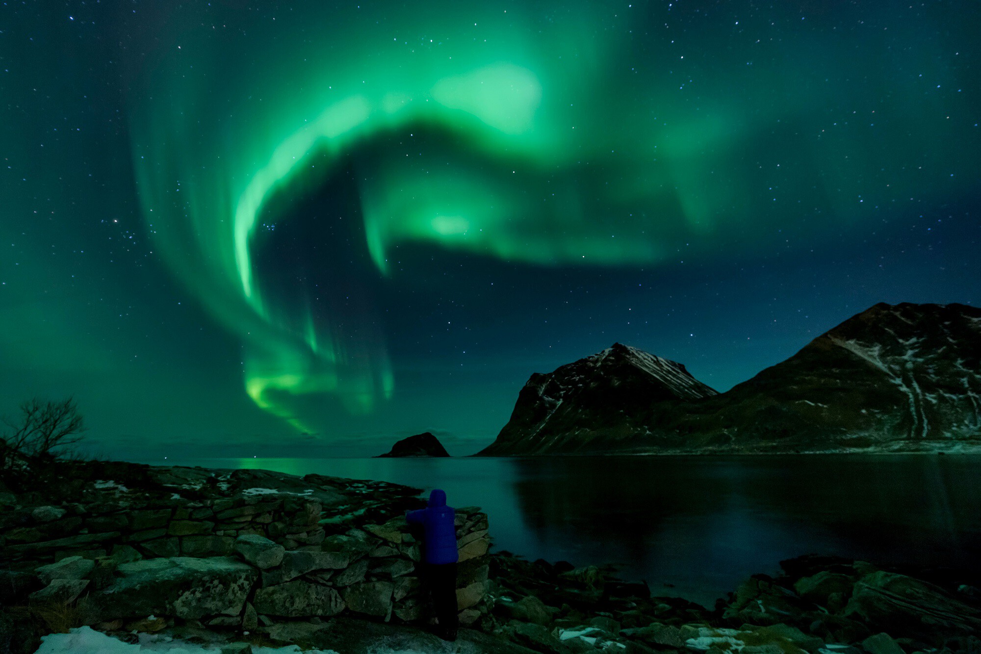 A person watches Northern Lights on March 9, 2018, in Utakleiv, northern Norway, Lofoten islands, within the Arctic Circle.