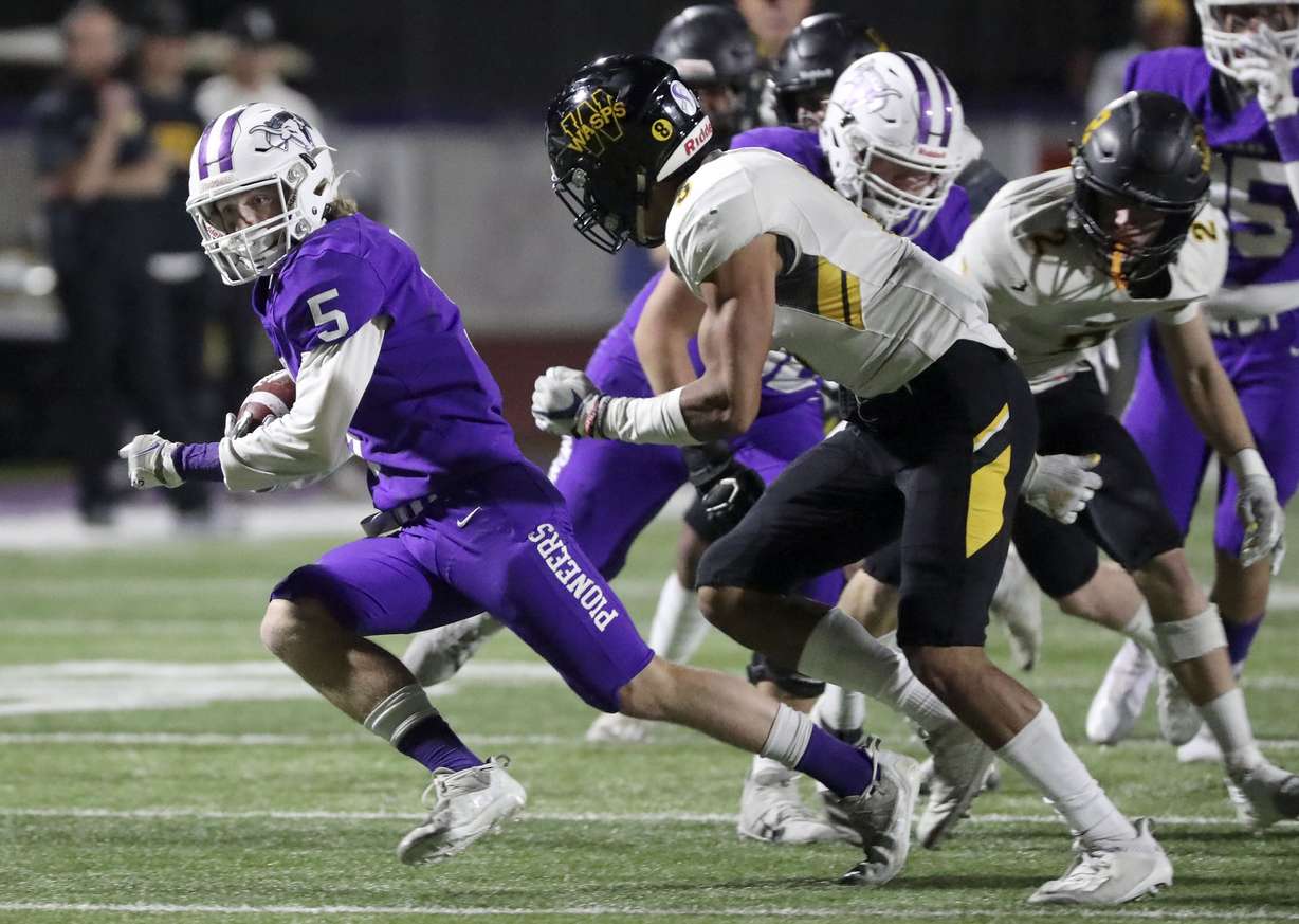 Lehi’s Isaac Mills runs with the ball past Wasatch's Jarinn Kalama during a 5A second-round football playoff game at Lehi High School in Lehi on Friday, Oct. 29, 2021.