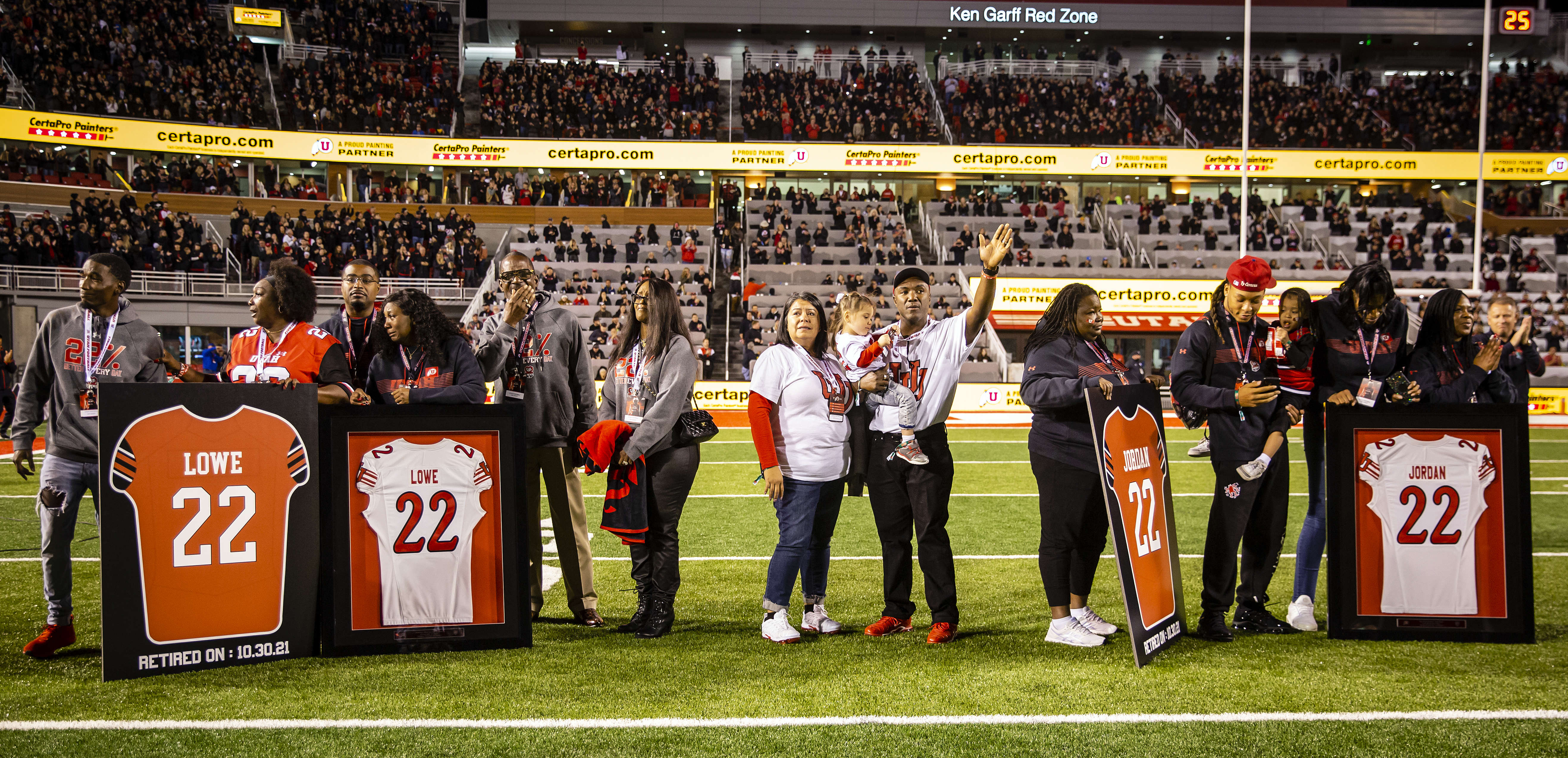 The families of Aaron Lowe and Ty Jordan stand with the retired jerseys during the retirement ceremony after the first quarter of the Utah UCLA game at Rice Eccles Stadium in Salt Lake City, Utah on Saturday, Oct. 30, 2021.