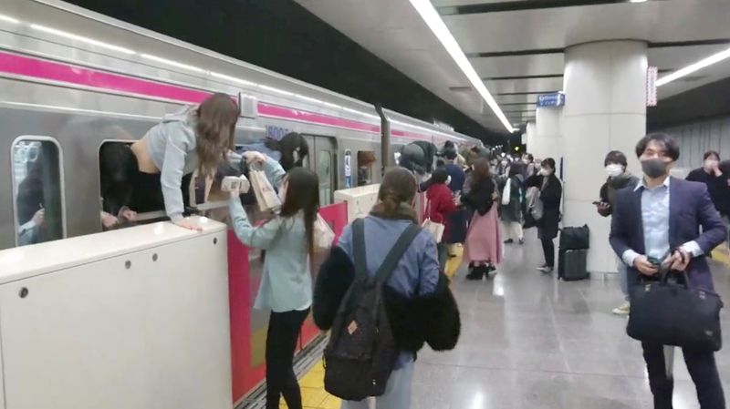 People escape through windows of a Tokyo train line following a knife, arson and acid attack, in Tokyo, Japan, on Sunday in this still image obtained from a social media video. 