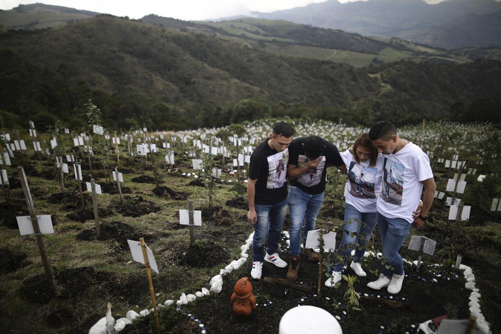 Relatives of Luis Enrique Rodriguez, who died of COVID-19, visit where he was buried on a hill at the El Pajonal de Cogua Natural Reserve, in Cogua, north of Bogota, Colombia, Monday, Oct. 25. Rodriguez died May 14. Relatives bury the ashes of their loved ones who died of coronavirus and plant a tree in their memory. The global death toll from COVID-19 topped 5 million on Monday
