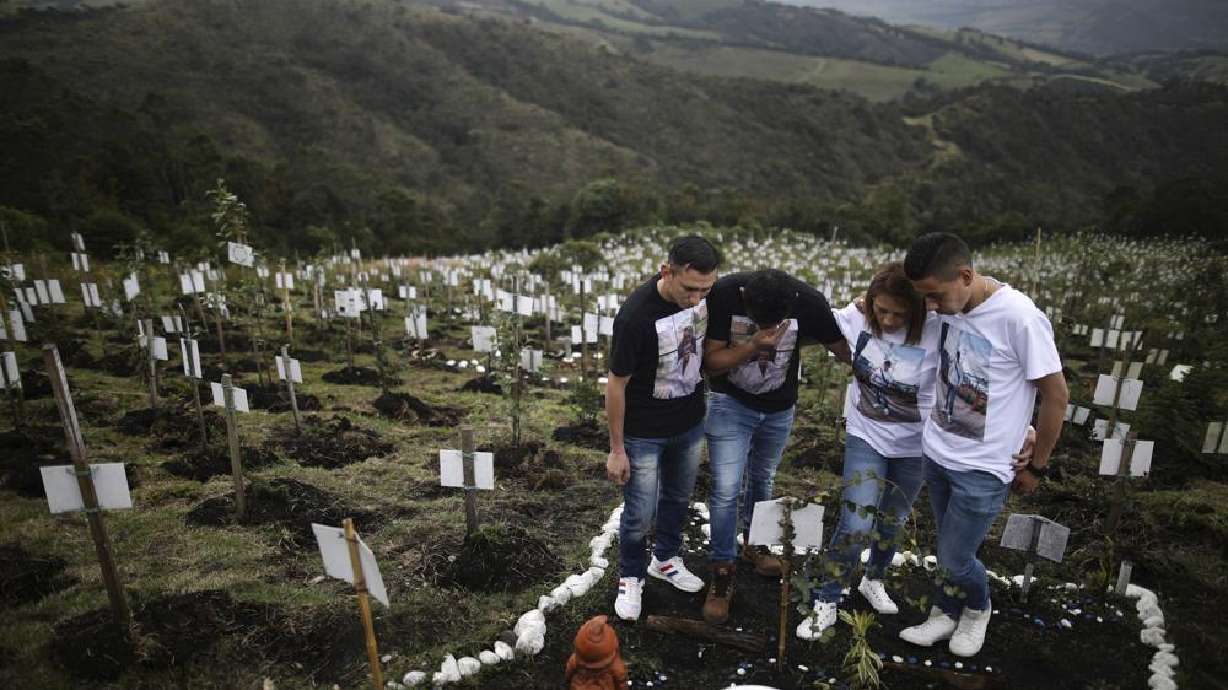 Relatives of Luis Enrique Rodriguez, who died of COVID-19, visit where he was buried on a hill at the El Pajonal de Cogua Natural Reserve, in Cogua, north of Bogota, Colombia, Monday, Oct. 25. Rodriguez died May 14. Relatives bury the ashes of their loved ones who died of coronavirus and plant a tree in their memory. The global death toll from COVID-19 topped 5 million on Monday