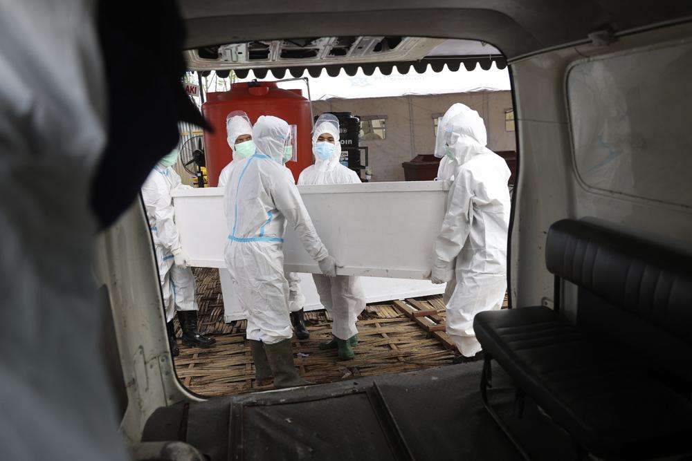 Health workers carry a coffin containing the body of a COVID-19 victim into an ambulance for burial in Surabaya, East Java, Indonesia, July 10, 2021. The global death toll from COVID-19 has topped 5 million, nearly two years into a crisis that has not only devastated poor countries but also humbled wealthy ones with first-rate health care systems.