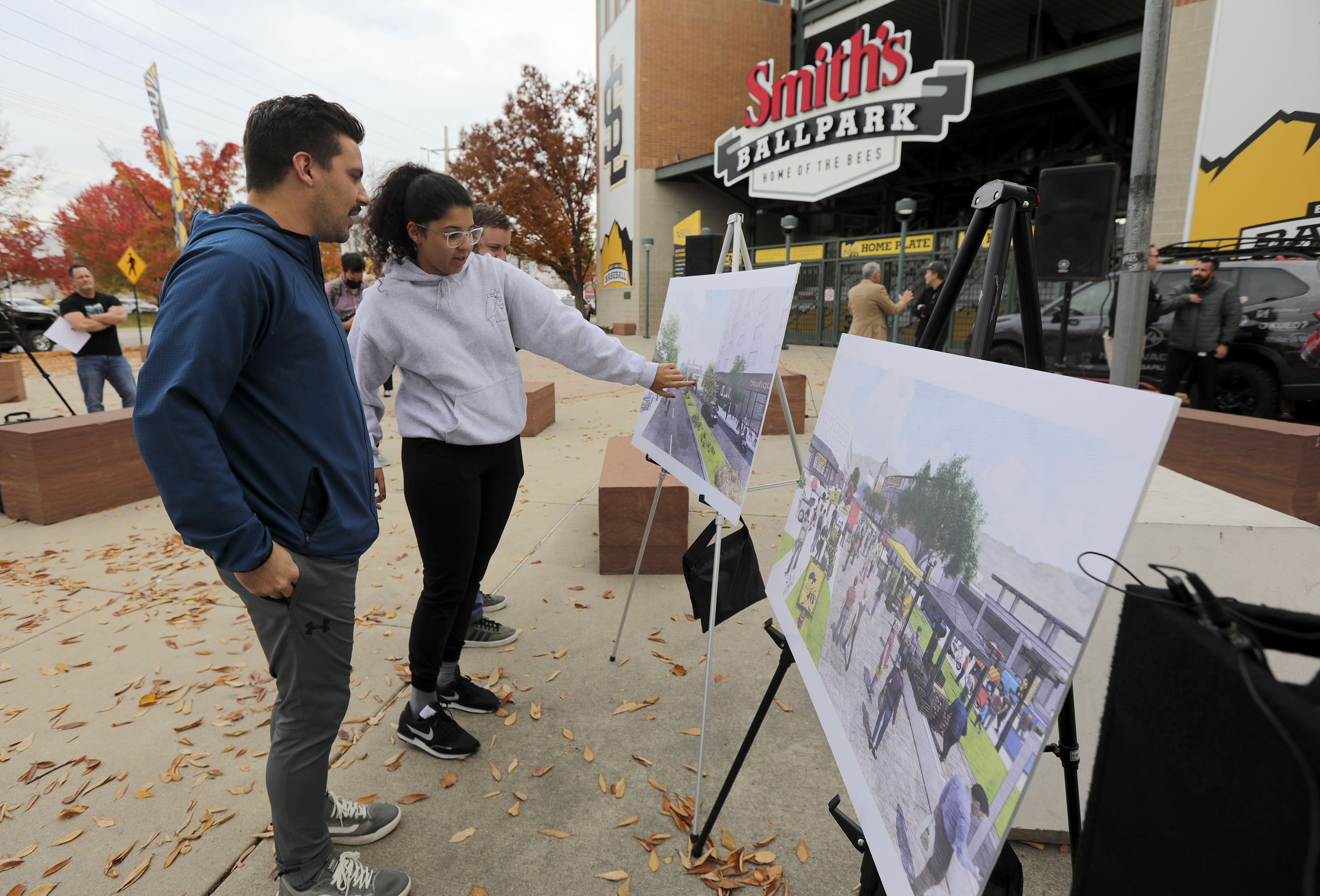Salt Lake Bees ticket account executives Tanner Lund and Sam Cook look at renditions of new plans for the Ballpark neighborhood, including a new library, during a press conference in Salt Lake City on Monday.
