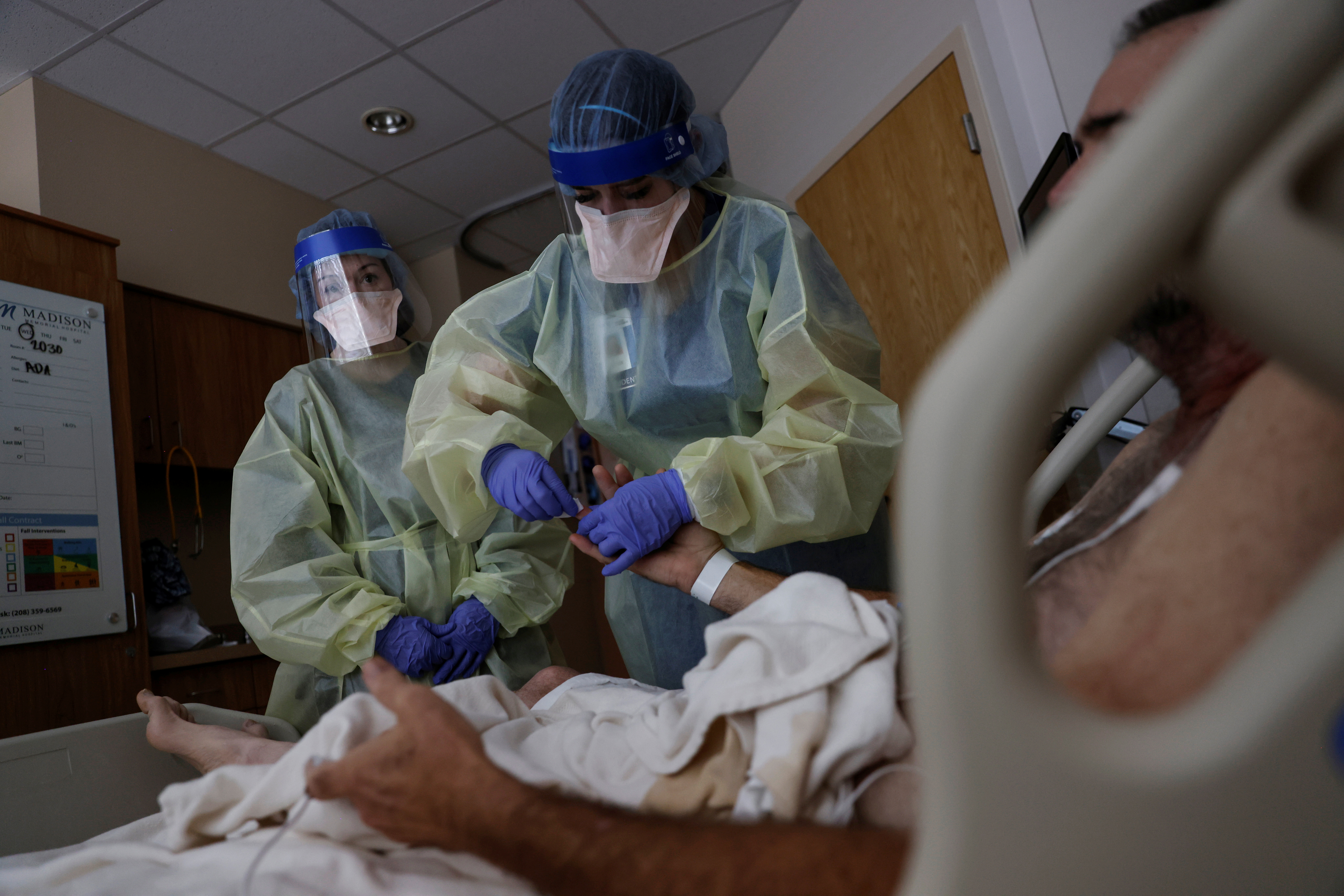 Registered Nurse Savanah Wagstaff watches as Aliza Burns, a nursing student at Brigham Young University–Idaho, treats a coronavirus disease-positive patient in his isolation room at Madison Memorial Hospital in Rexburg, Idaho, Sunday.