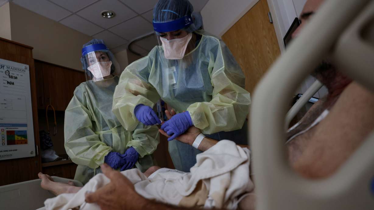 Registered Nurse Savanah Wagstaff watches as Aliza Burns, a nursing student at Brigham Young University–Idaho, treats a coronavirus disease-positive patient in his isolation room at Madison Memorial Hospital in Rexburg, Idaho, Sunday.