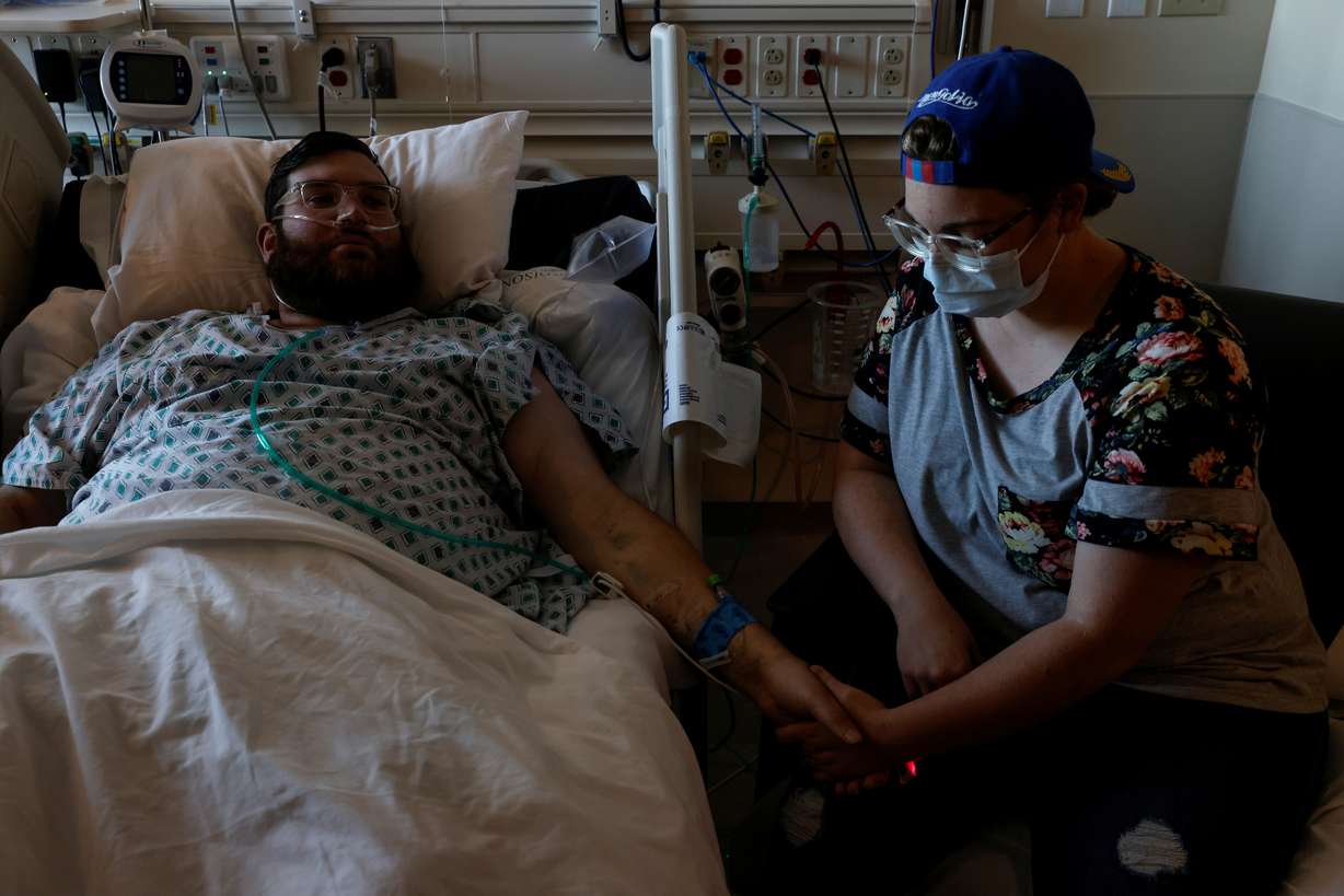 Andrew Pawson, 30, a coronavirus disease positive patient in recovery after spending over a month in isolation wards, holds the hand of his wife Isobel inside his room at Memorial Hospital in Rexburg, Idaho, U.S., October 28, 2021.