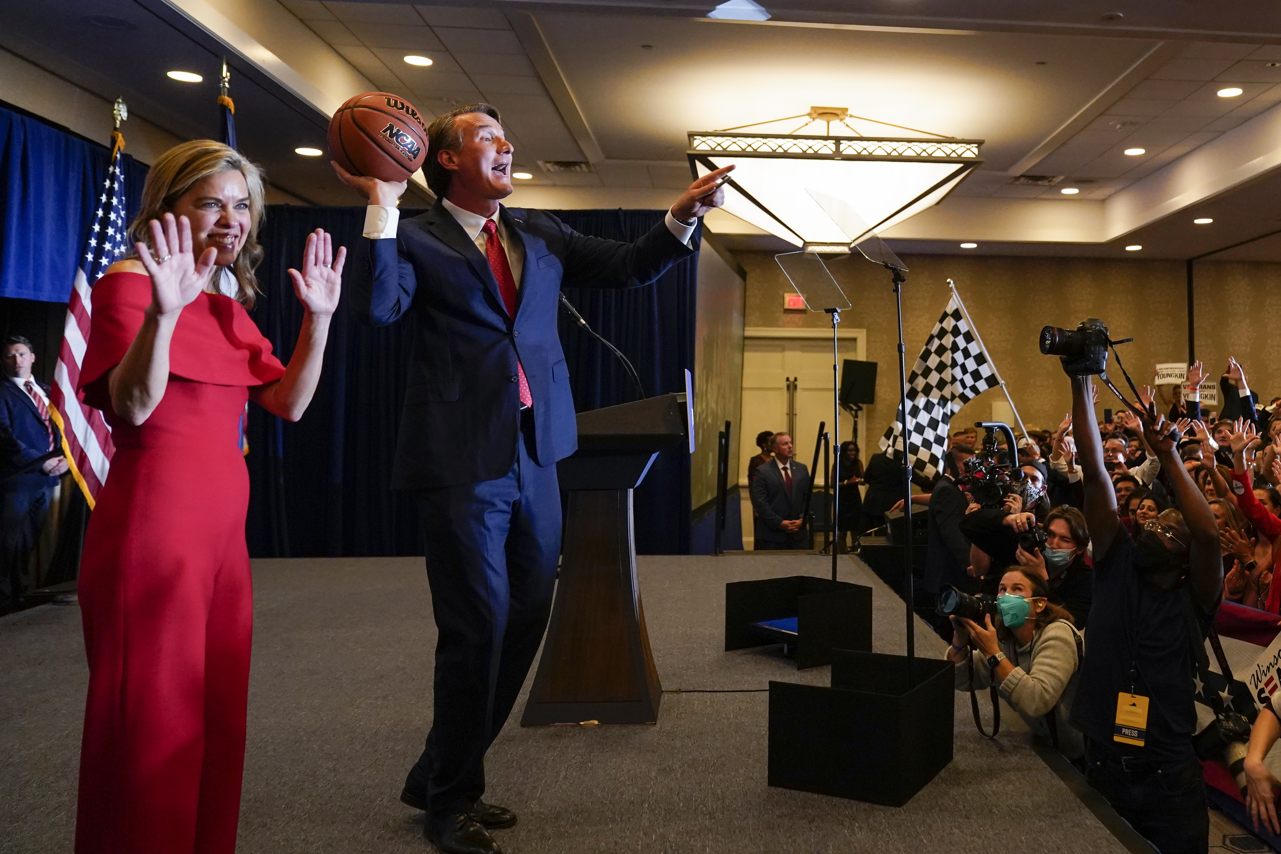 Virginia Gov.-elect Glenn Youngkin tosses a signed basketball to supporters as his wife Suzanne waves at an election night party in Chantilly, Va., early Wednesday after he defeated Democrat Terry McAuliffe.