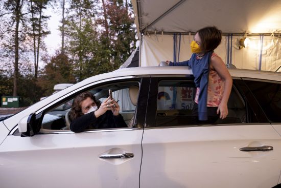 An excited Cate Zeigler-Amon, 10, hangs out of the car as she waits with her mom, Sara Zeigler, to receive her first dose of COVID-19 vaccine at the Viral Solutions vaccination and testing site in Decatur, Ga. on the first day COVID-19 vaccinations were available for children from 5 to 12 on Wednesday. The pair arrived one and a half hours before the site opened to be first in line.