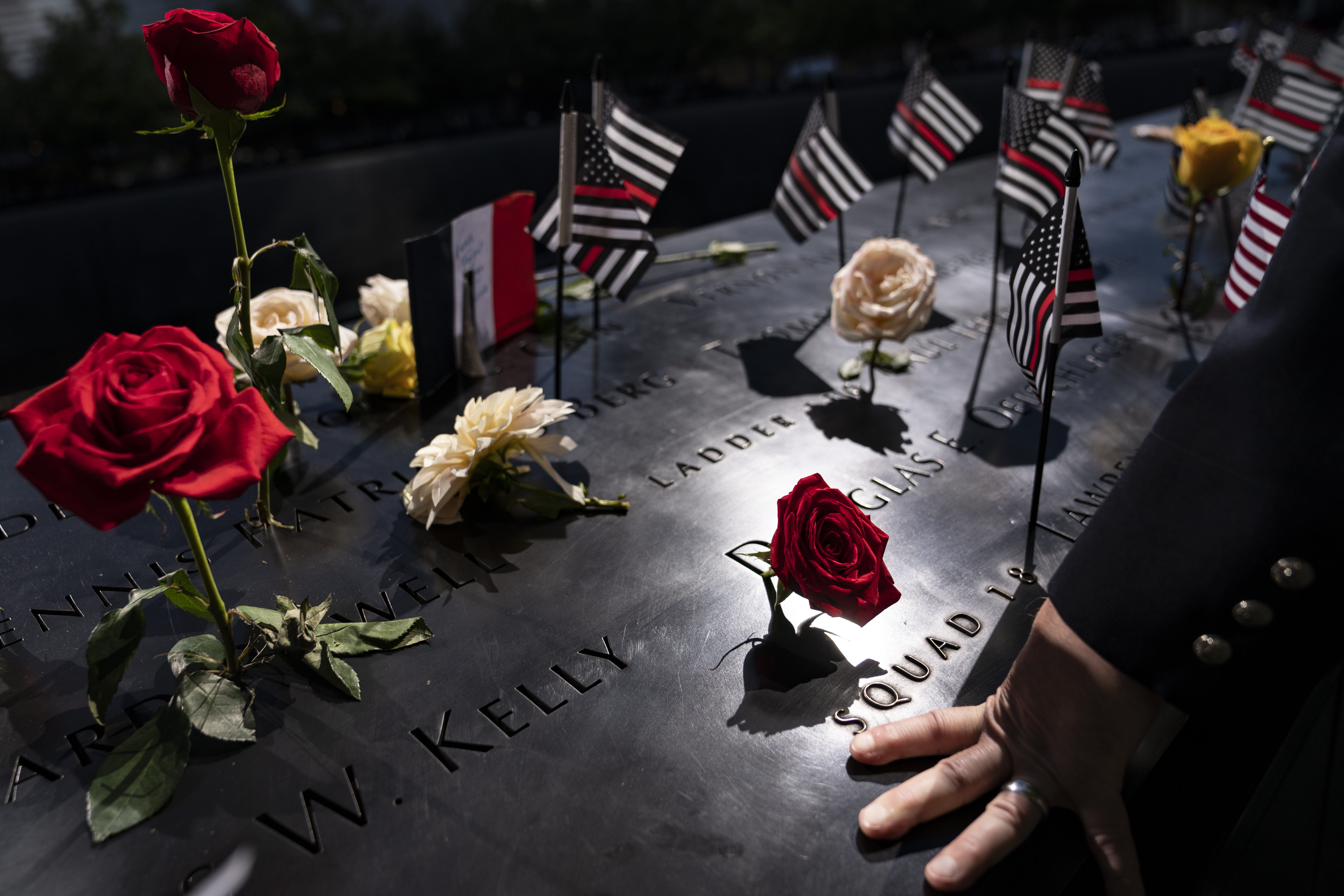 A firefighter places his hand on the name engravings on the south pool during ceremonies to commemorate the 20th anniversary of the Sept. 11 terrorist attacks, Sept. 11, 2021, at the National September 11 Memorial & Museum in New York. The FBI released hundreds of pages of newly declassified documents Wednesday about its long effort to explore connections between the Saudi government and the Sept. 11 attacks.