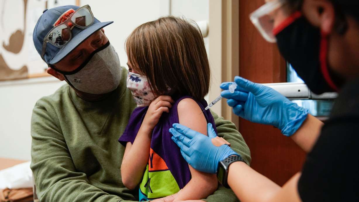 Jason Miller comforts his daughter, Teagan Miller, 7, as she receives her first dose of the COVID-19 vaccine from nurse Tenzin Drongsar at South Main Public Health Center in Salt Lake City on Wednesday.