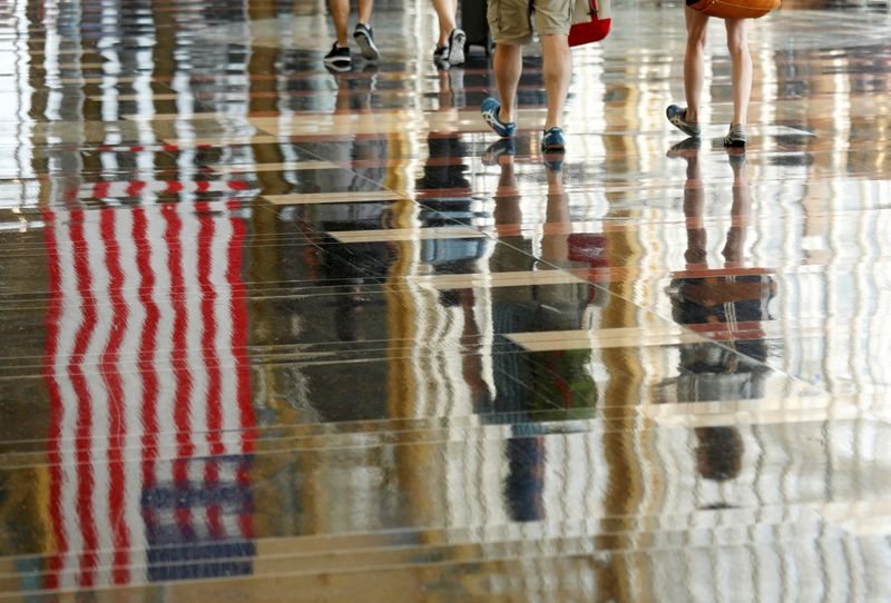 A U.S. flag is reflected on the floor as passengers make their way through Reagan National Airport in Washington, July 1, 2016.
