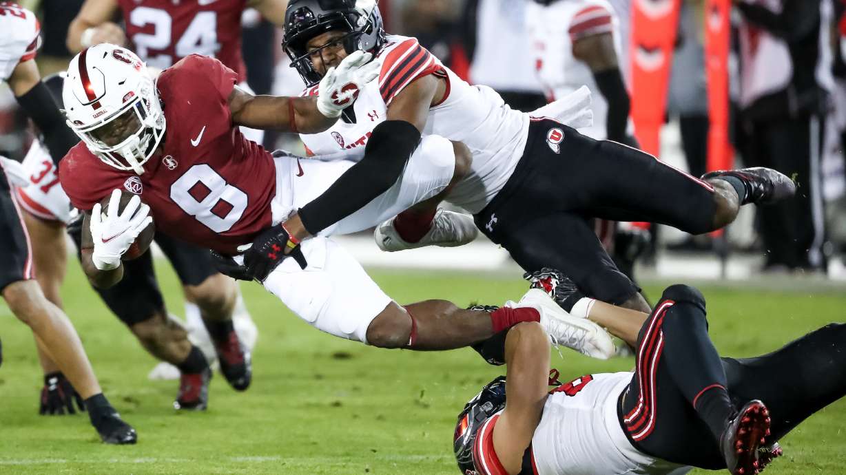 Utah Utes wide receiver Bryson Reeves (19) and linebacker Jonah Elliss (83) tackle Stanford Cardinal running back Nathaniel Peat (8) on a punt return in Stanford, Calif. on Friday, Nov. 5, 2021.