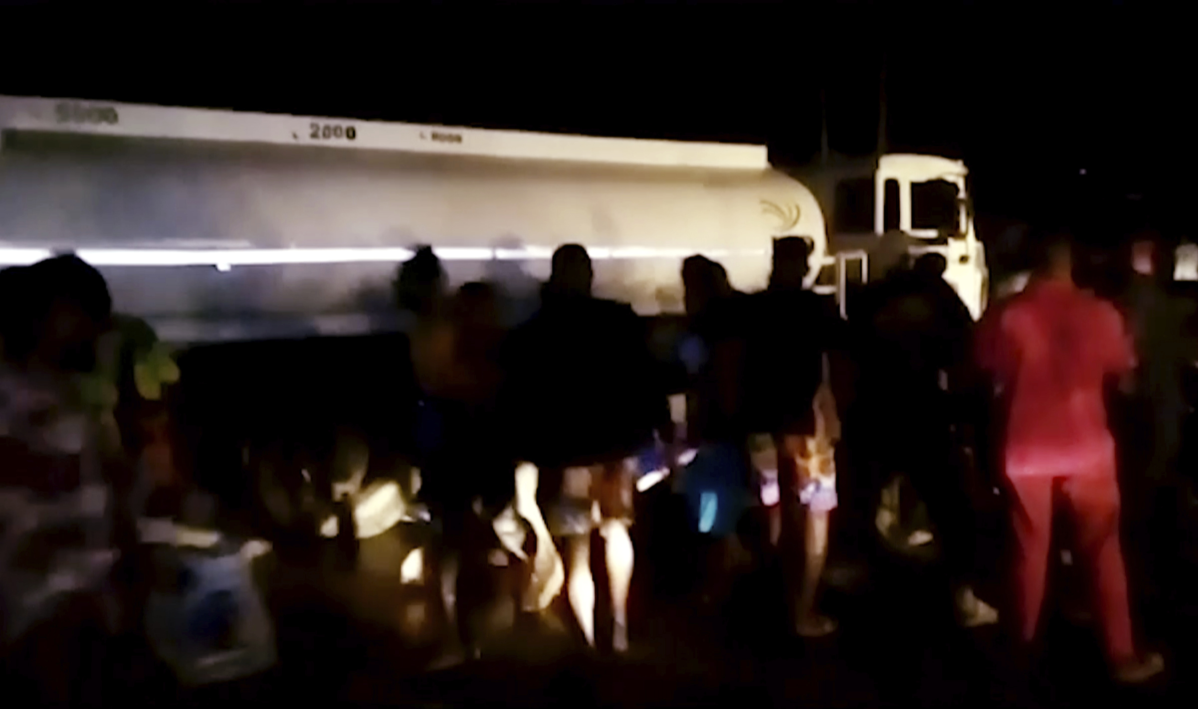 People gather around an oil tanker to collect leaking fuel before it exploded near Sierra Leone's capital, killing at least 92 people and severely injuring dozens of others, officials and witnesses said Saturday. The explosion took place late Friday after a bus struck the tanker in Wellington, a suburb just to the east of Freetown.