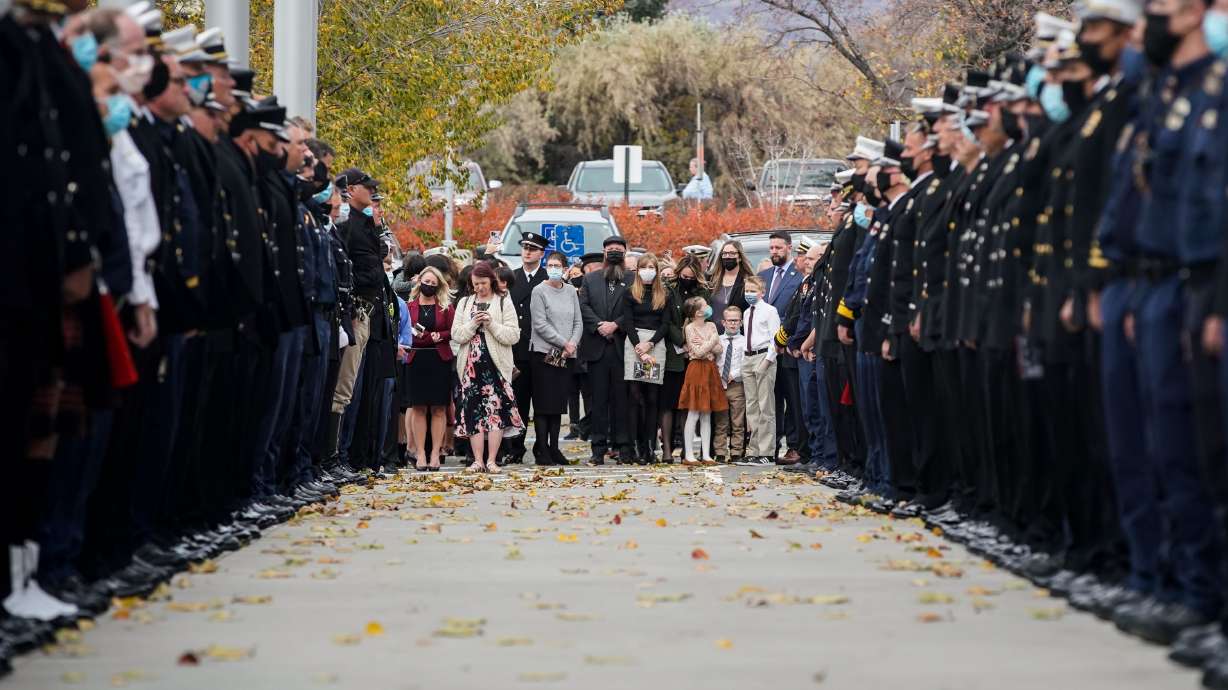 Family member of 39-year veteran firefighter Merrill Bone stands in unity for a guard of honor after his funeral service on Saturday at Olympus High School in Holladay.