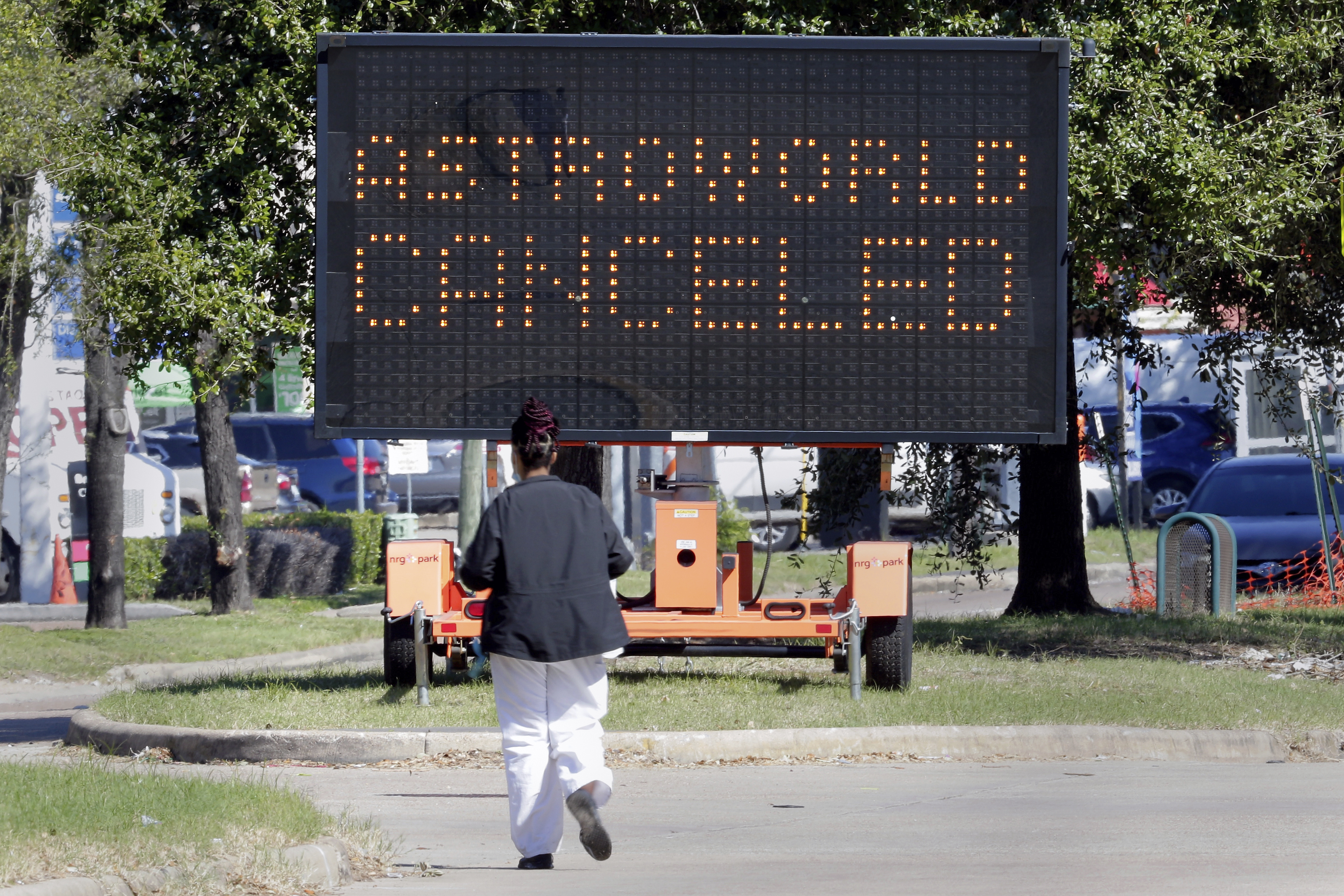 A pedestrian cross Main Street in front of a sign announcing the cancellation of Astroworld on Saturday in Houston. Several people died and numerous others were injured in what officials described as a surge of the crowd at the music festival while Travis Scott was performing Friday night.  