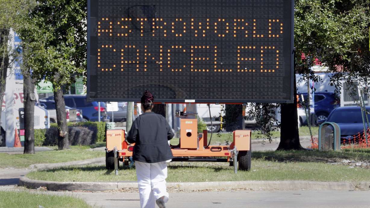 A pedestrian cross Main Street in front of a sign announcing the cancellation of Astroworld on Saturday in Houston. Several people died and numerous others were injured in what officials described as a surge of the crowd at the music festival while Travis Scott was performing Friday night.