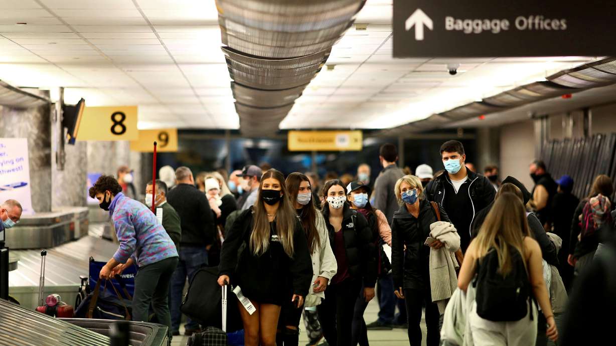 Travelers wearing protective face masks to prevent the spread of the coronavirus disease reclaim their luggage at the airport in Denver, Nov. 24, 2020. The United States is expecting a flood of international visitors crossing its borders by air and by land on Monday after lifting travel restrictions for much of the world's population.