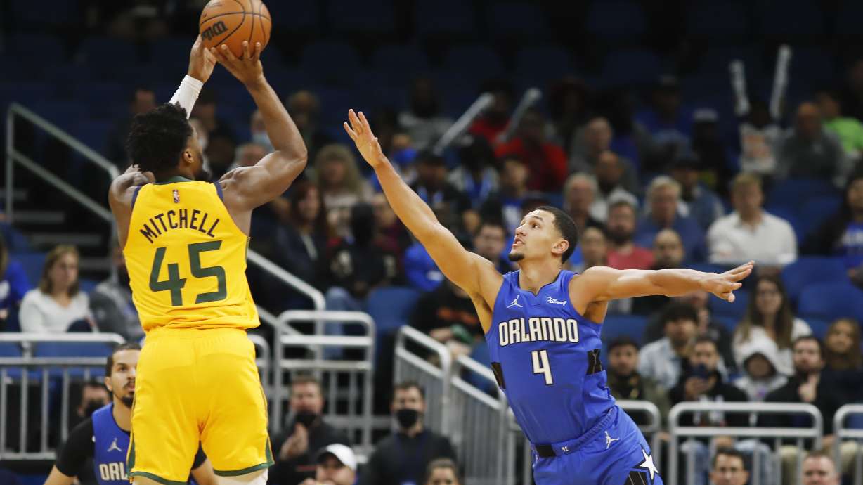 Orlando Magic guard Jalen Suggs (4) defends against a shot by Utah Jazz guard Donovan Mitchell (45) during the first half of an NBA basketball game, Sunday, Nov. 7, 2021, in Orlando, Fla.