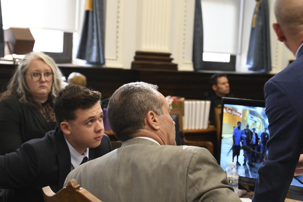 Kyle Rittenhouse listens to defense attorneys Mark Richards and Corey Chirafisi during Rittenhouse's trial at the Kenosha County Courthouse in Kenosha, Wisconsin, on Friday. Rittenhouse is accused of killing two people and wounding a third during a protest over police brutality in Kenosha, last year.