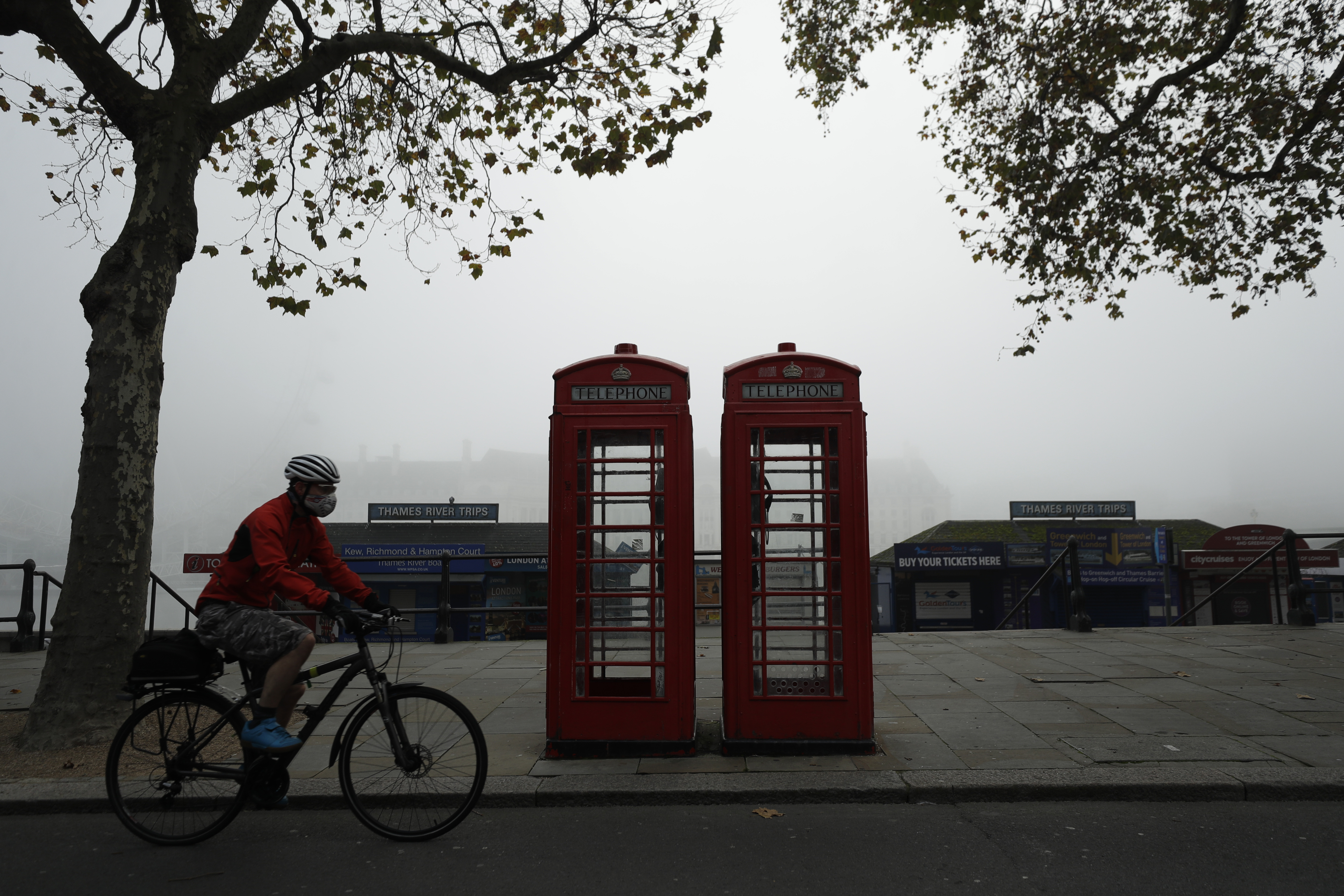 A cyclist passes traditional red phone boxes in London Nov. 5, 2020. Thousands of Britain’s iconic red phone boxes will be protected from removal under new rules, the telecoms regulator said Tuesday.