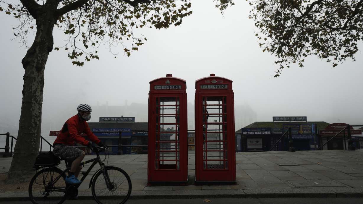 A cyclist passes traditional red phone boxes in London Nov. 5, 2020. Thousands of Britain’s iconic red phone boxes will be protected from removal under new rules, the telecoms regulator said Tuesday.