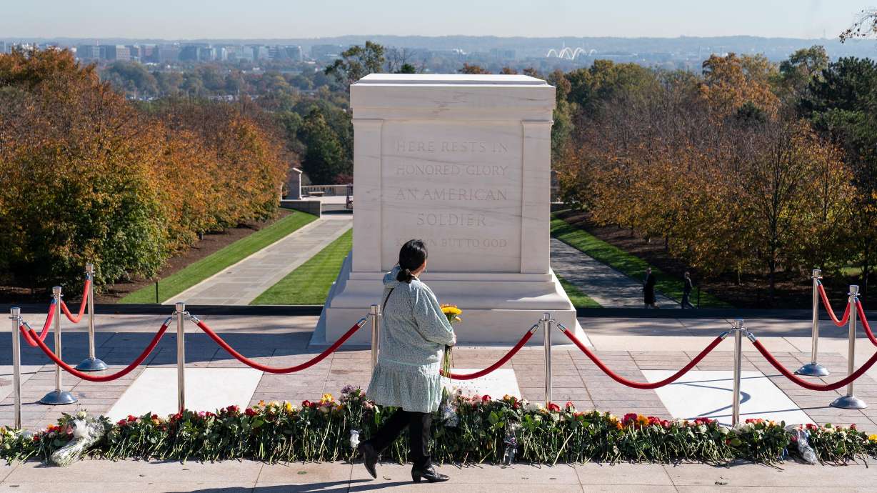 A woman arrives to place flowers during a centennial commemoration event at the Tomb of the Unknown Soldier, in Arlington National Cemetery, Tuesday, in Arlington, Va.